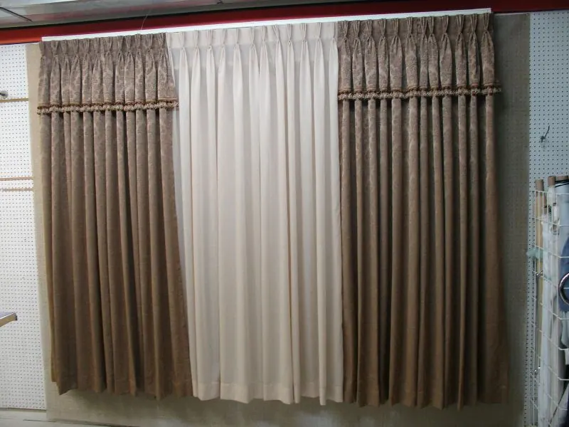 Three pleated curtain samples in brown, white and taupe on display