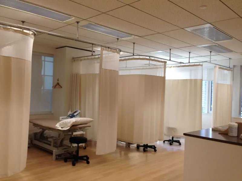 Rideaux de séparation crème sur rails dans une clinique aux lits de soins
