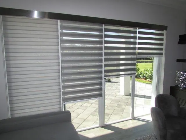 Stores alternés gris devant une porte coulissante donnant sur un patio