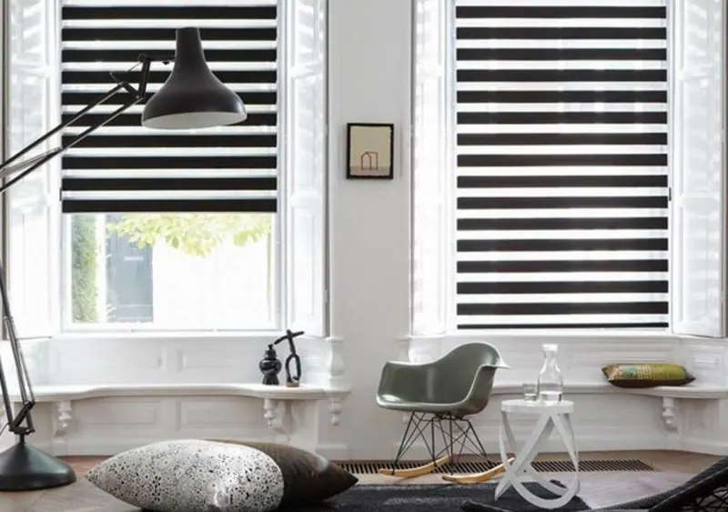Stores zébrés noir et blanc sur deux fenêtres, salon aux coussins