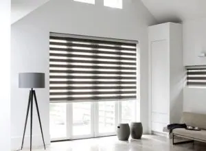 Store zébré gris foncé dans un salon blanc, lampe sur trépied