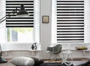 Stores zébrés noir et blanc sur fenêtres jumelles, fauteuil moderne