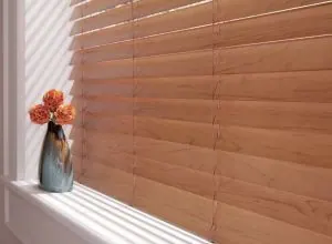 Store horizontal en bois de teinte miel, gros plan, vase orange